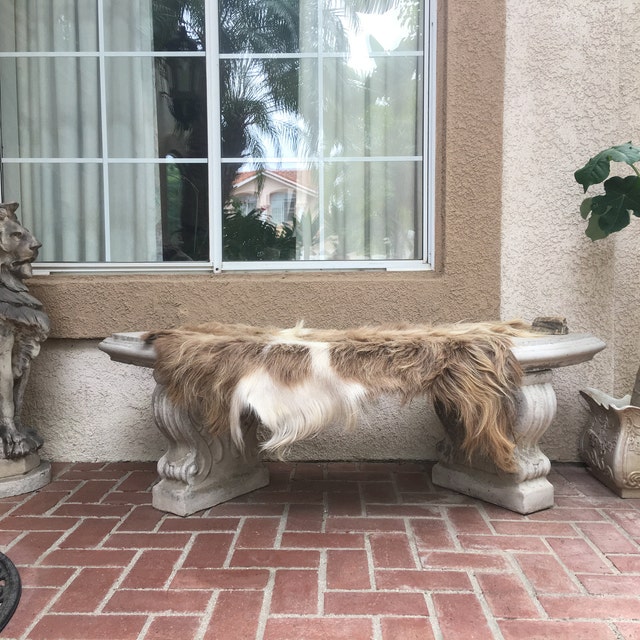brown and white sheepskin hide shown on a concrete bench.
