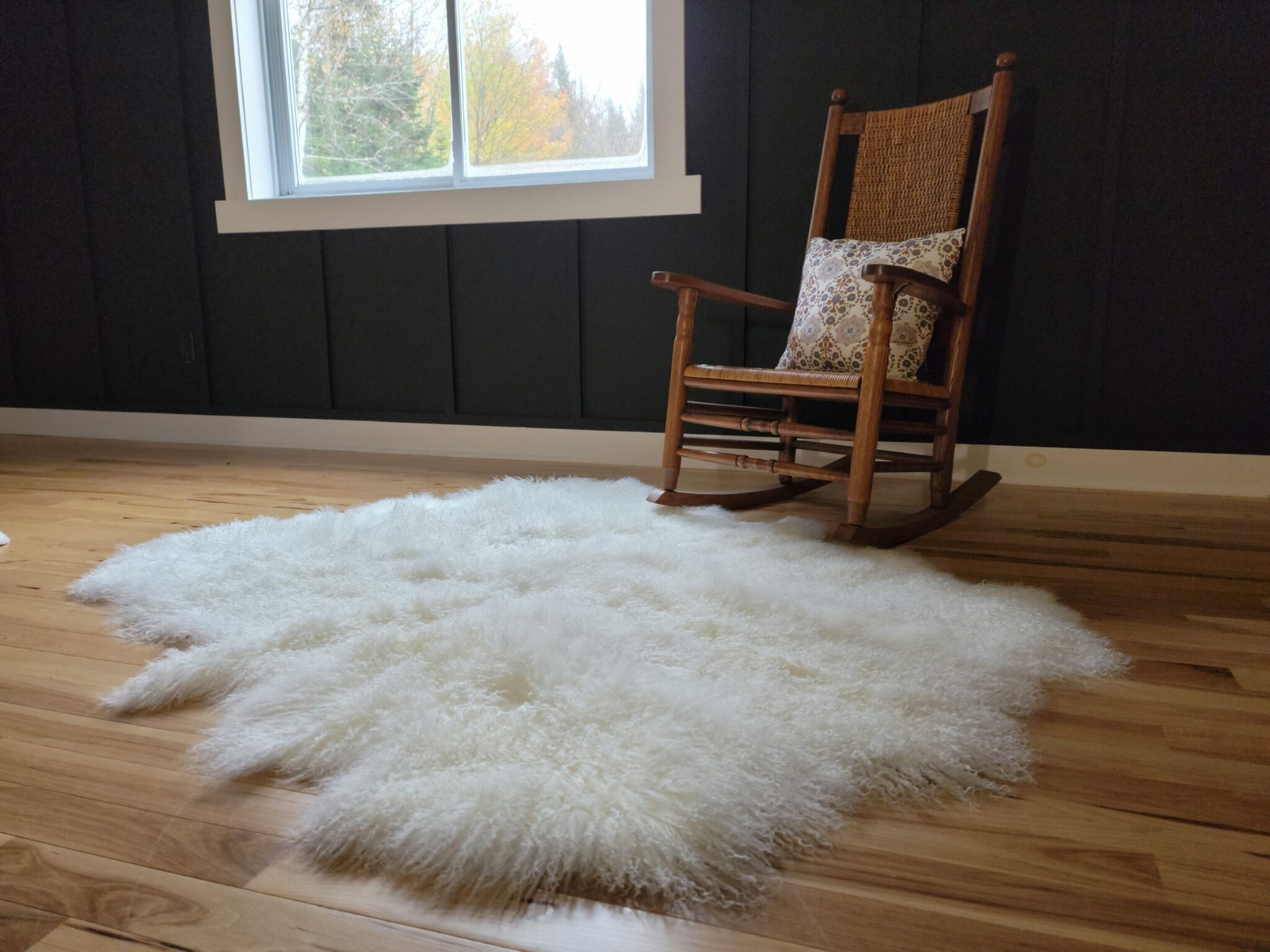 Soft white organic shape sexto (6 pelt) rug on the floor by a rocking chair