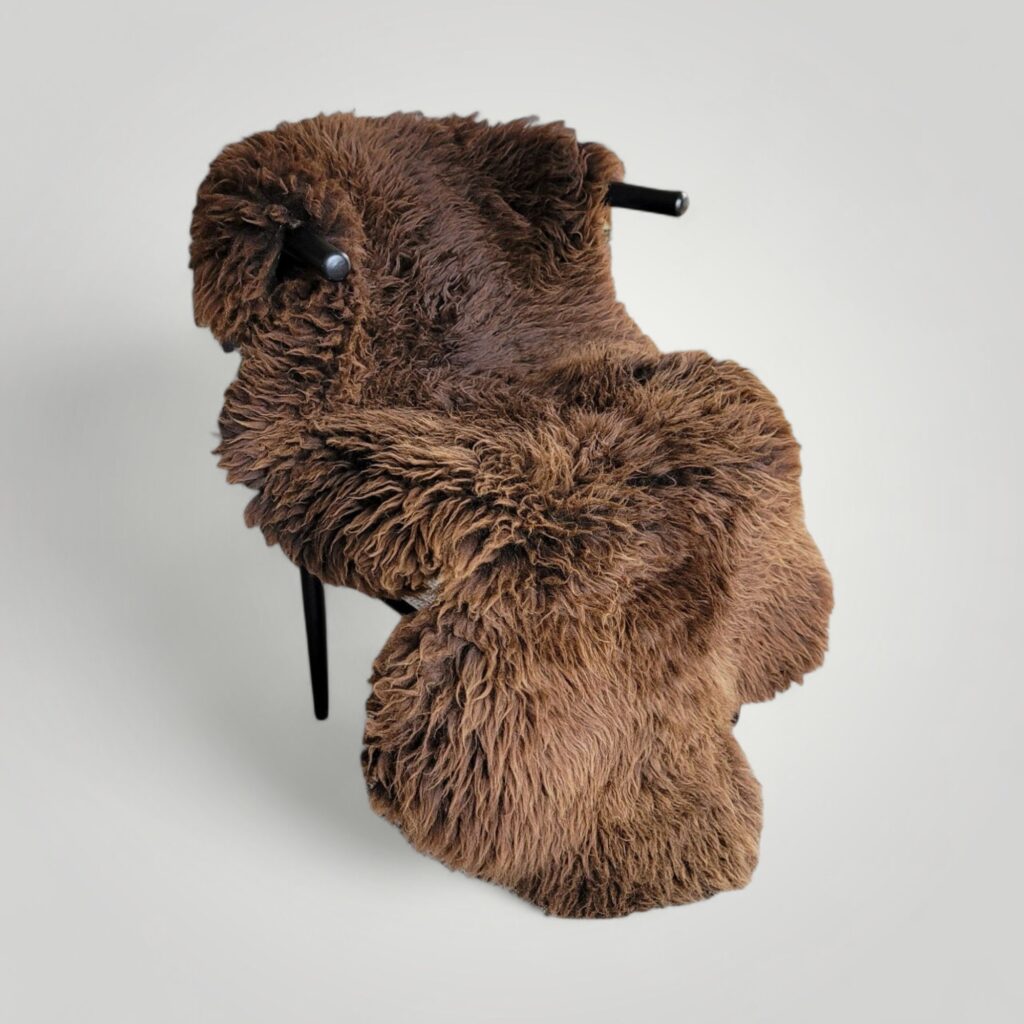 Big lofty brown sheepskin rug placed over entire chair to use as a cozy throw