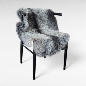Gray Gotland sheepskin pelt shown in a chair used as a seat cushion and throw