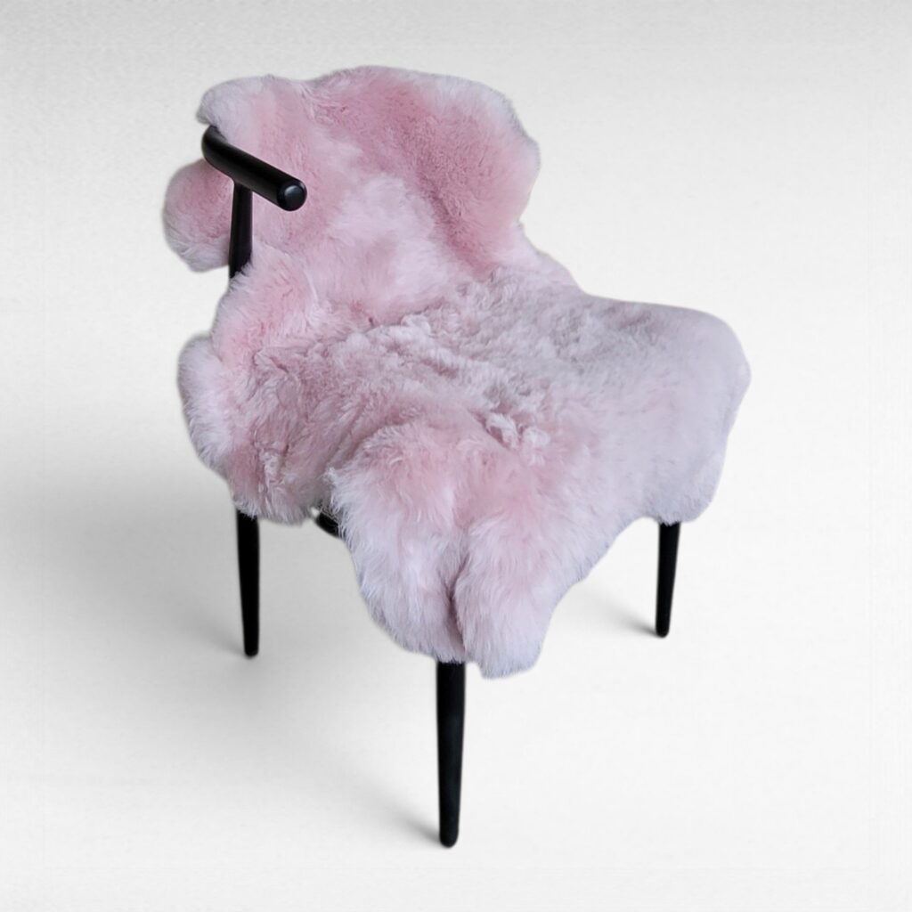 Light pink single pelt fur rug made using 100% genuine sheepskin displayed in a modern chair