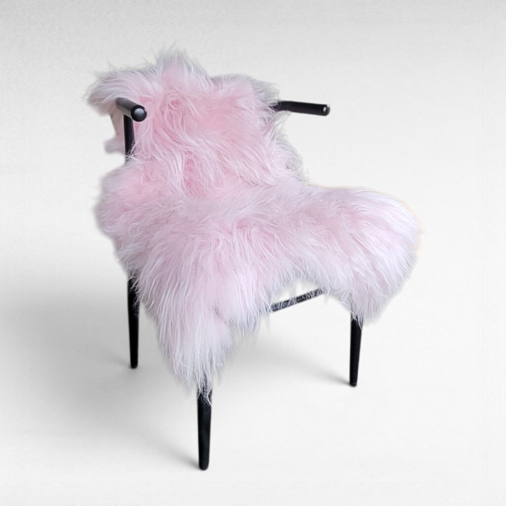 Light pink shag fur rug made using 100% genuine sheepskin displayed in a modern chair