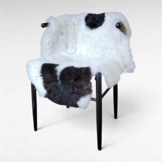 Dark cool brown spotted sheepskin with flecks on a white background displayed on a chair