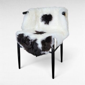 Fancy dark brown spotted short wool lambskin displayed on a chair