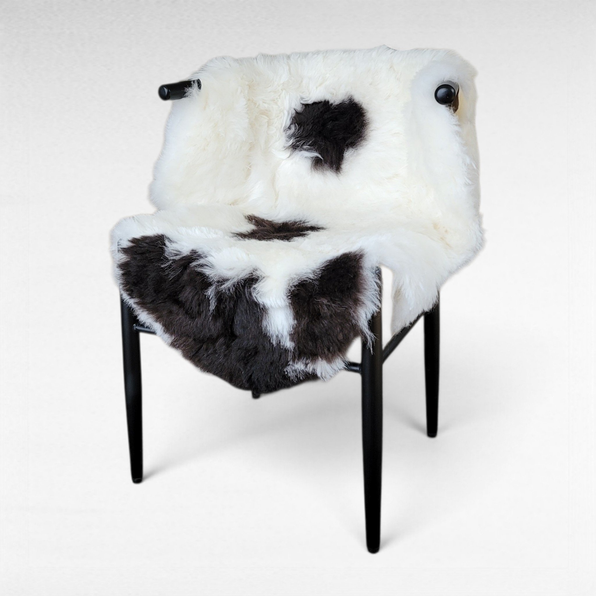 Fancy dark brown spotted short wool lambskin displayed on a chair