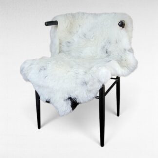 primitive shorn Icelandic sheepskin with flecks and a few brown spots displayed on a chair